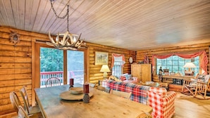 A log cabin interior with a wooden dining table, chairs, a sofa, and a rocking chair. - Private Wooded Cabin: 7 Mi to Mount Snow! (Wilmington)