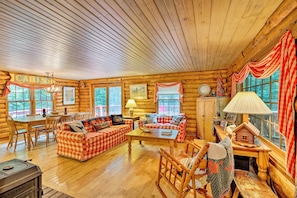 A log cabin interior with a checkered sofa set, wooden dining table, rocking chair, and a lamp. - Private Wooded Cabin: 7 Mi to Mount Snow! (Wilmington)