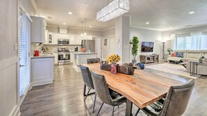 A spacious kitchen with white cabinets, a central island, and a dining area with a wooden table and chairs.