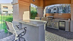 Une terrasse extérieure dotée d’un bar en pierre, de coins salon et d’un espace barbecue.