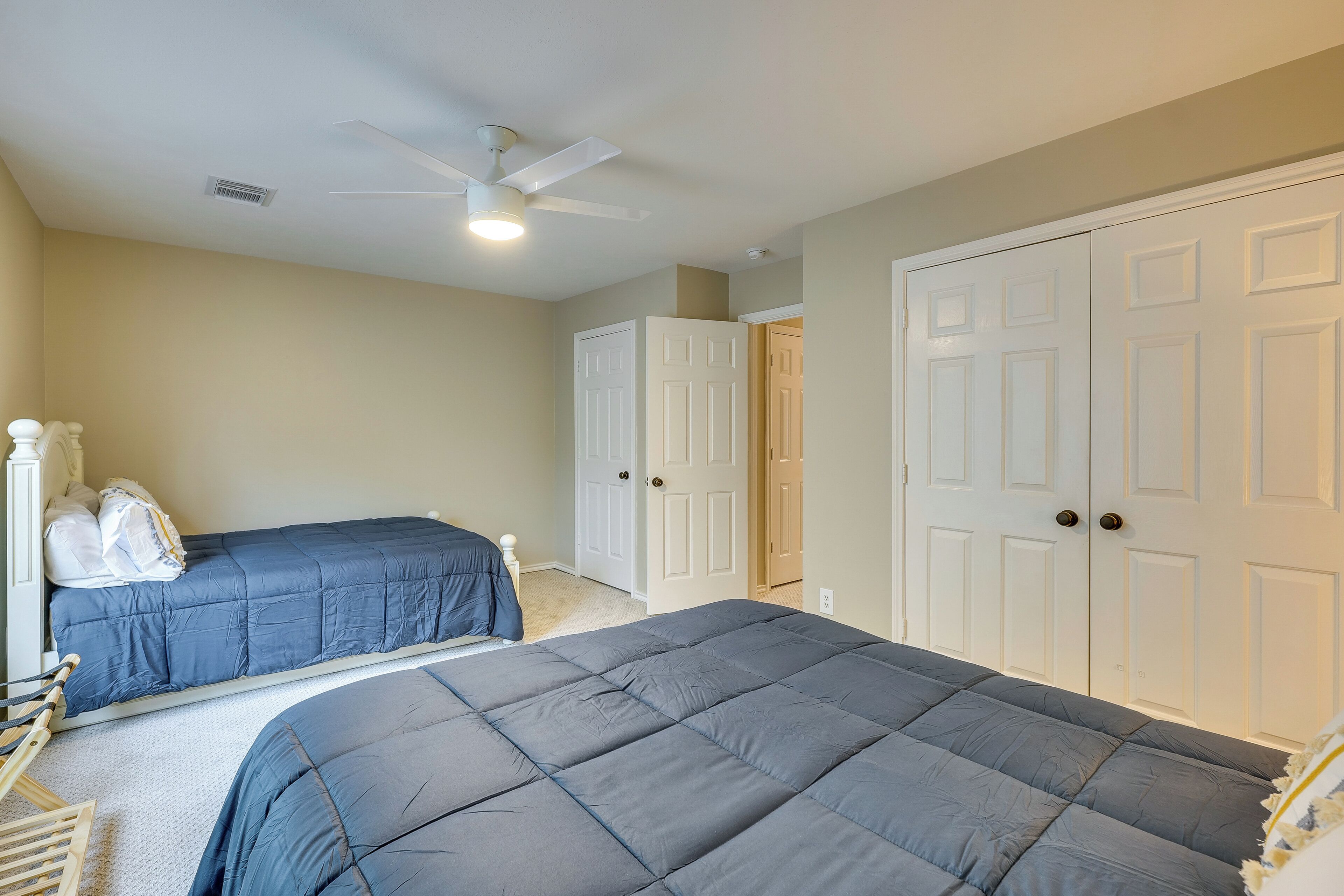 A bedroom with two beds, a ceiling fan, and white doors.