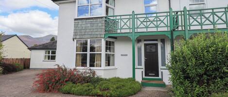 A two-story house with a green porch and a black front door.