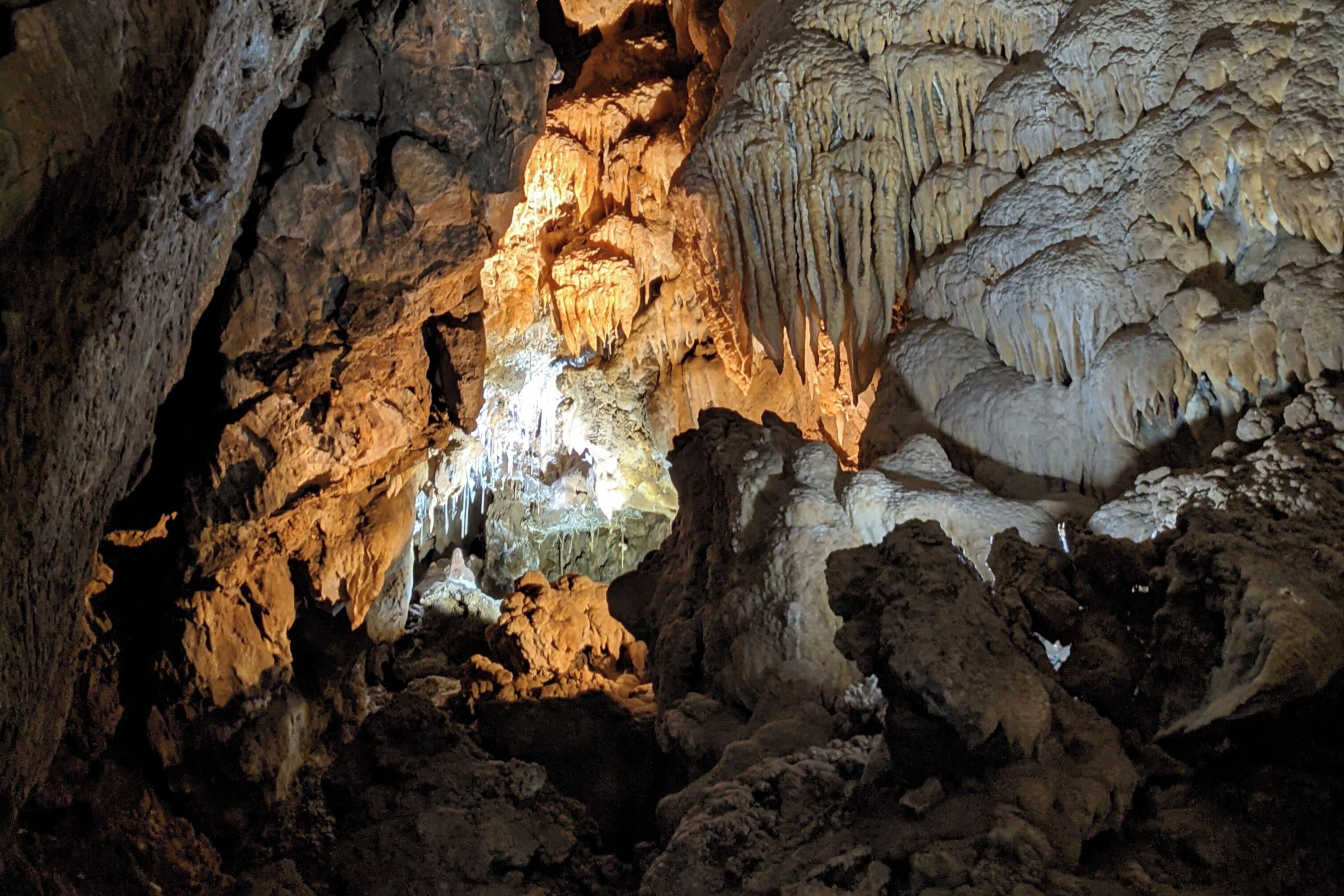 Eine Höhle mit Stalaktiten und Stalagmiten, beleuchtet durch künstliches Licht.