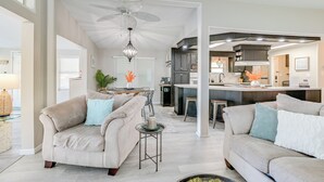 A spacious living room with two beige sofas, a coffee table, and a ceiling fan.