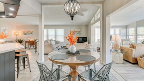 A spacious living area with a round dining table, modern chairs, and a ceiling fan.