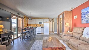 Eine moderne Küche mit Holzausstattung, einer Mikrowelle und einem Kühlschrank. Es gibt eine Essecke mit Tisch und Stühlen sowie ein gemütliches Wohnzimmer mit Sofa und Couchtisch.