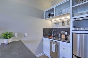 A modern kitchen with white cabinetry, a stainless steel refrigerator, and a countertop with a sink and various kitchen utensils. - San Marcos Apartment w/ Off-street Parking! (San Marcos)