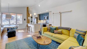 A modern living room with a yellow sofa, a coffee table, and a dining area with a table and chairs.
