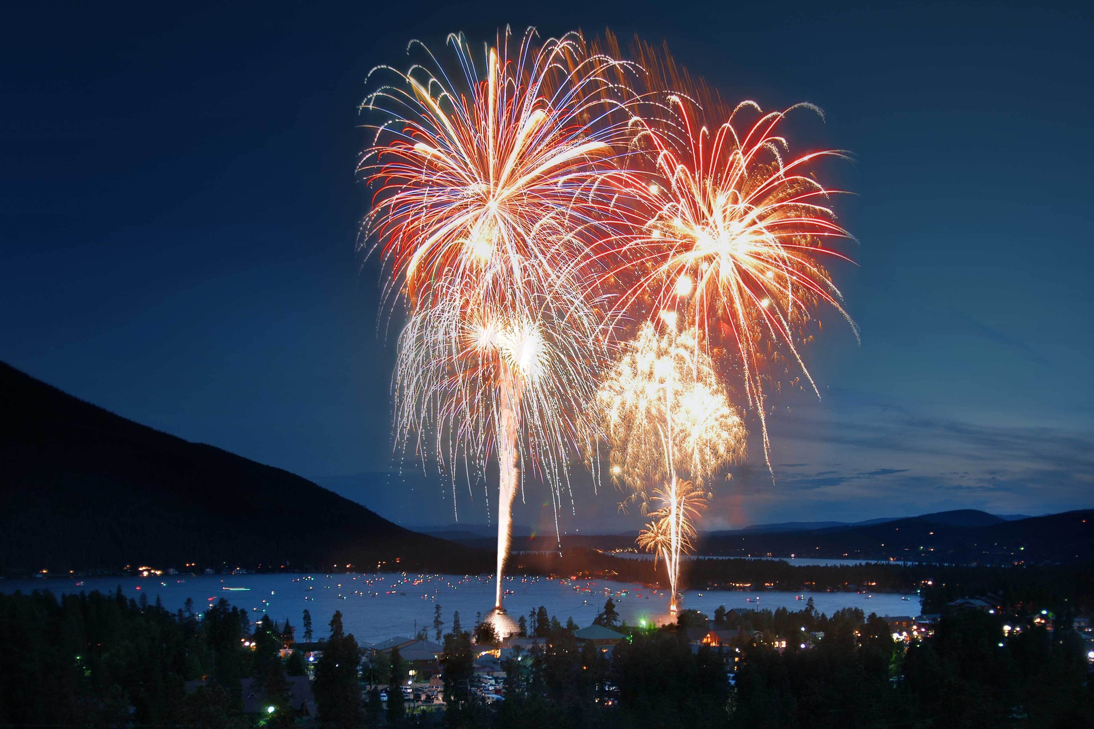 A nighttime view of a lake with fireworks display.