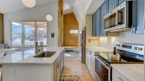 A modern kitchen with a central island, stainless steel appliances, and wooden accents.