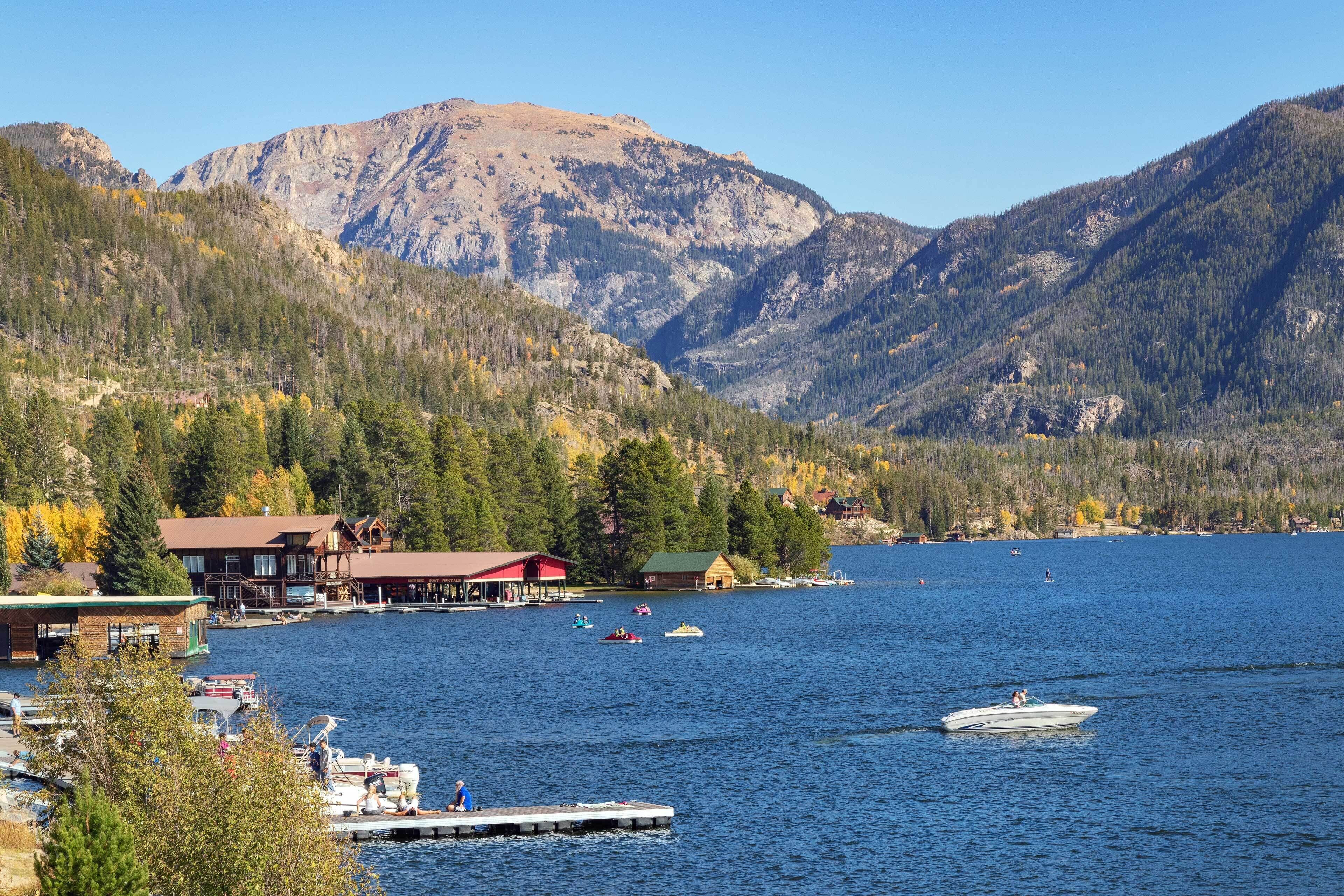 A lakeside property with a dock, boats, and cabins.
