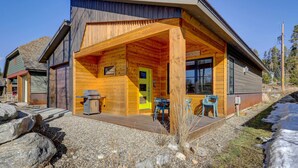 A log cabin with a covered porch, a grill outside, and a clear sky.