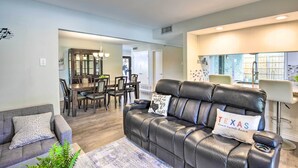 A modern living room with a leather sofa, a gray armchair, and a dining area with a wooden table and chairs. - Movie Room & Private Pool: Richardson Retreat (Richardson)