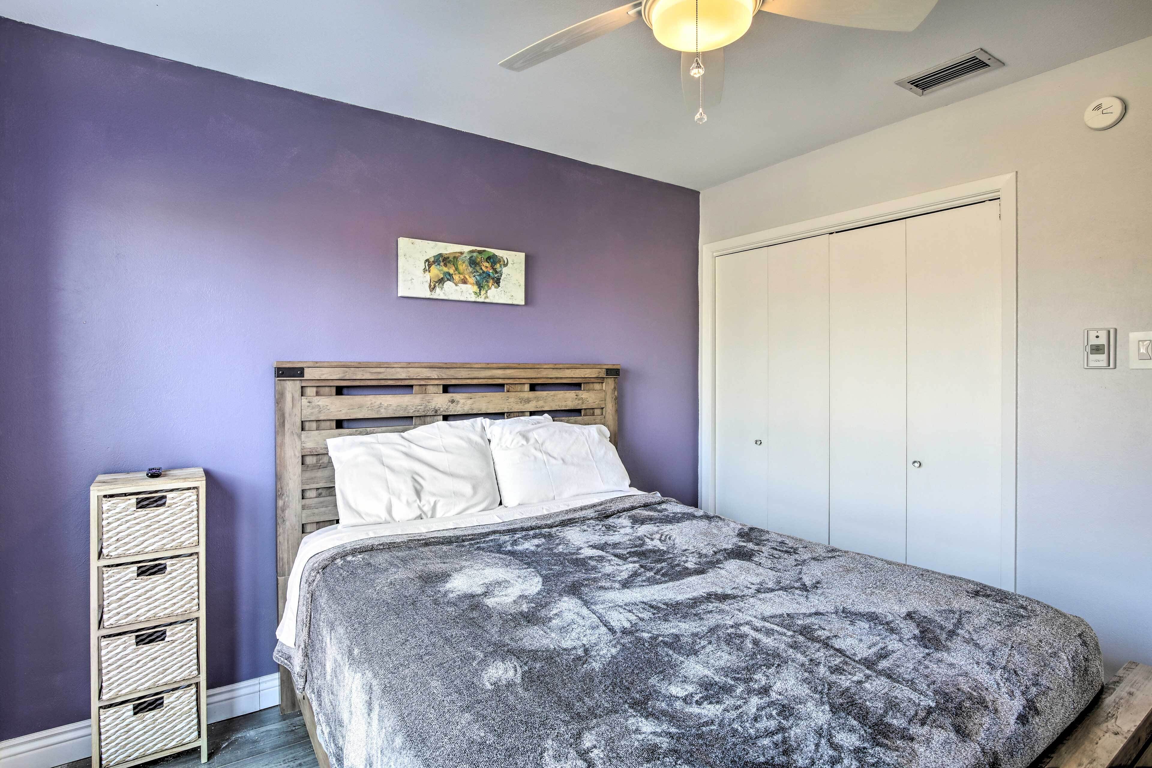 A bedroom with a bed, a wooden headboard, a white wardrobe, and a wall-mounted artwork.