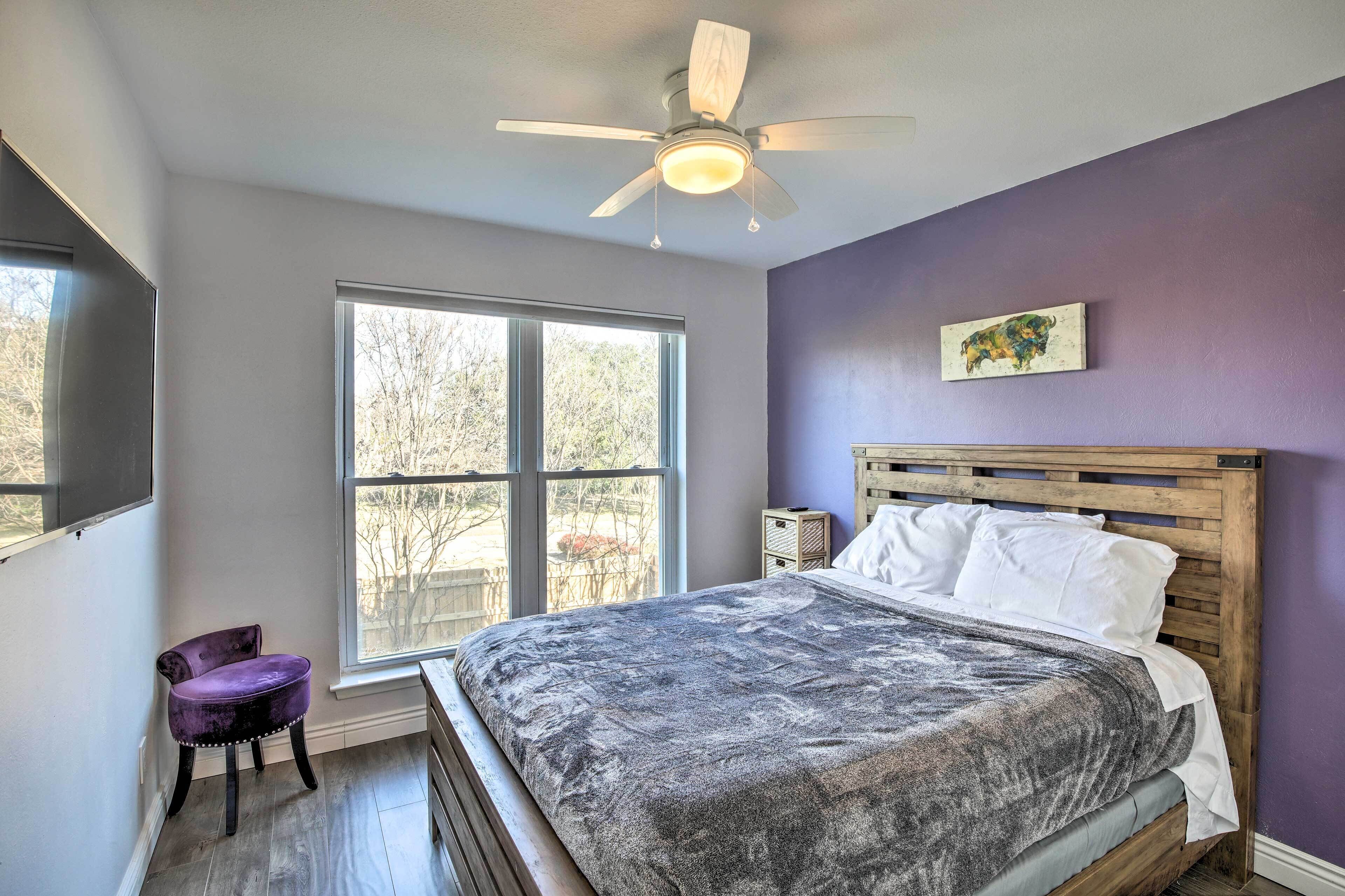 A bedroom with a bed, a window, a ceiling fan, and a chair.