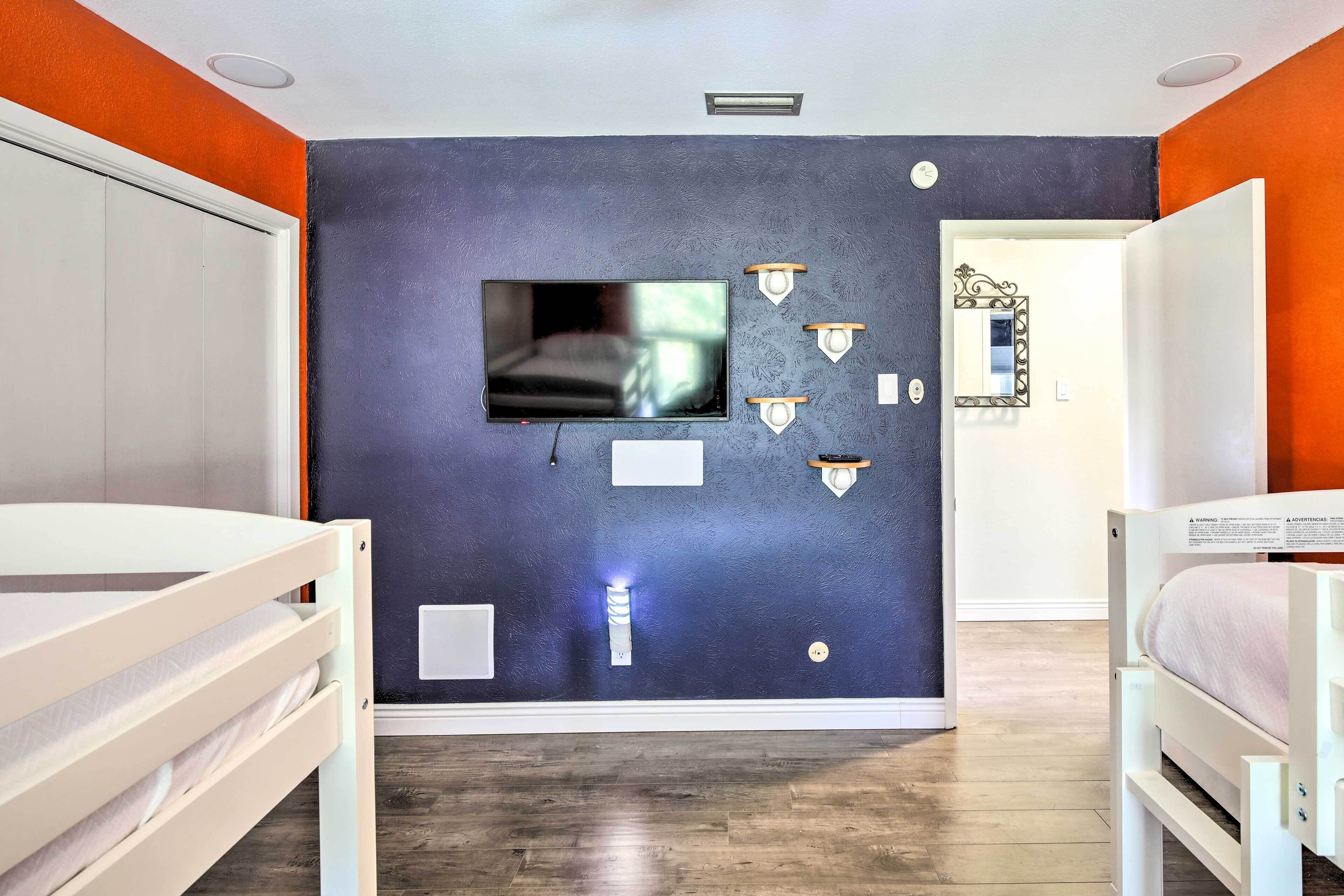 A bedroom with a television mounted on the wall, bedside tables, a mirror, and a bed.