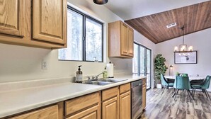 A kitchen with wooden cabinets, a dishwasher, and a dining area with teal chairs and a table. - ~ 8 Mi to State Park & Trails: Pine Mountain Home (Pine)