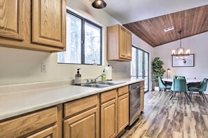 Una cocina moderna con armarios de madera, lavavajillas y un ventanal grande.