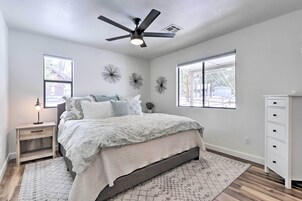 Un dormitorio con cama, mesita de noche, cómoda, ventilador de techo y decoración mural.