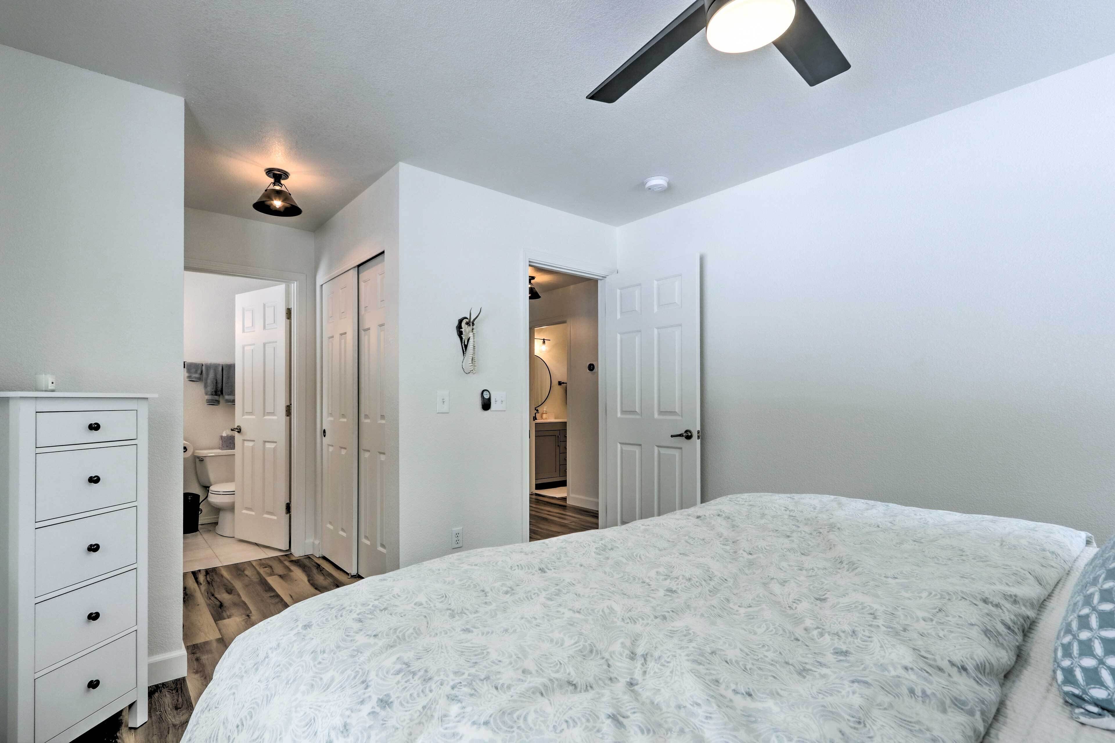 A bedroom with a bed, a dresser, and a ceiling fan.
