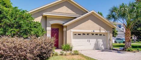 A residential house with a red door, beige exterior, and a white garage door.