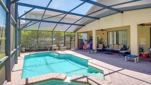 A covered outdoor swimming pool with lounge chairs and a patio area. - Sunny Villa w/ Lanai: 17 Mi to Disney! (Davenport)