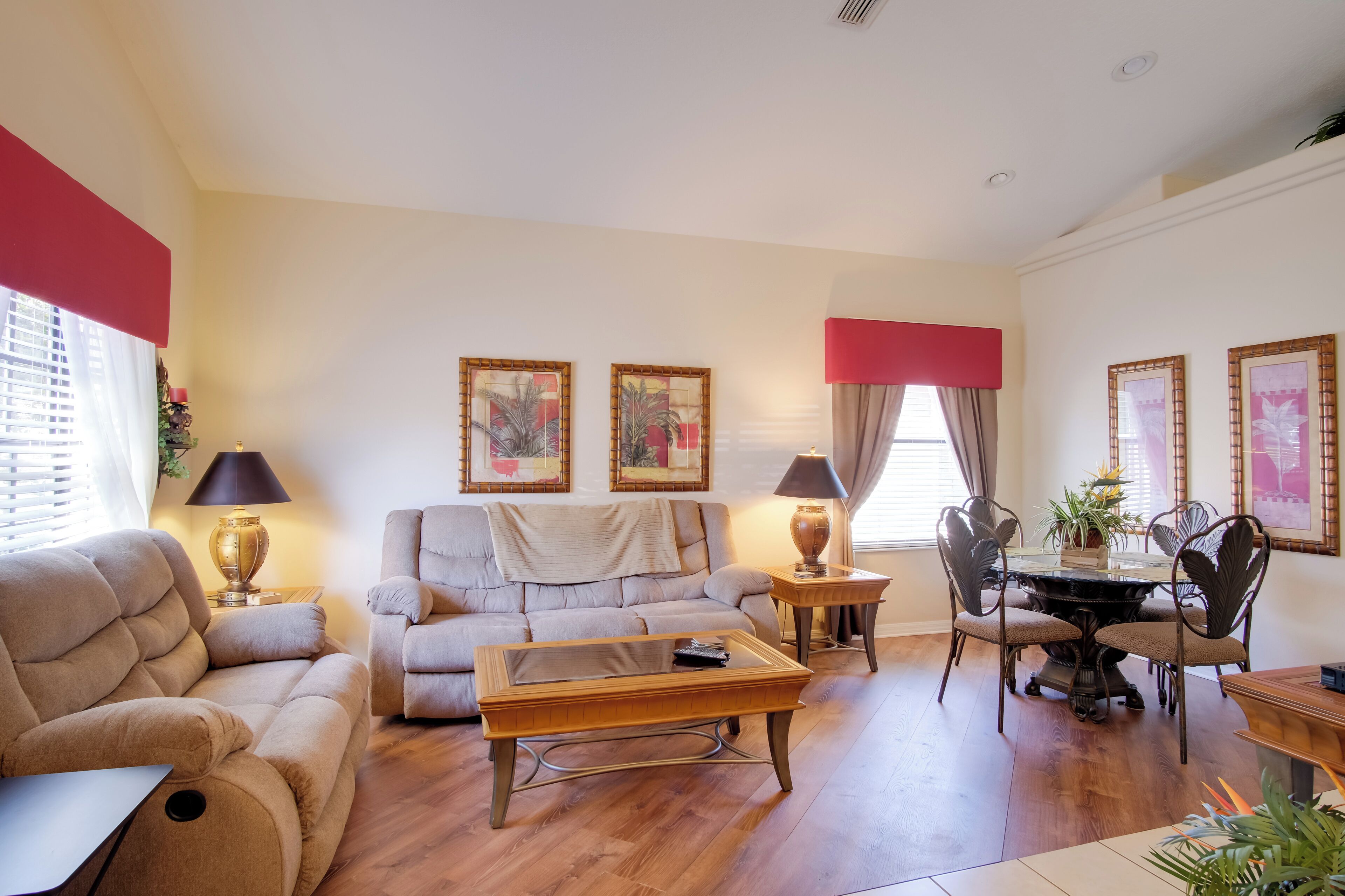 A living room with a sofa, a coffee table, a dining table with chairs, and two lamps.