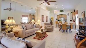 A spacious living room with a sofa, chairs, a dining table, and a ceiling fan. - Sunny Villa w/ Lanai: 17 Mi to Disney! (Davenport)