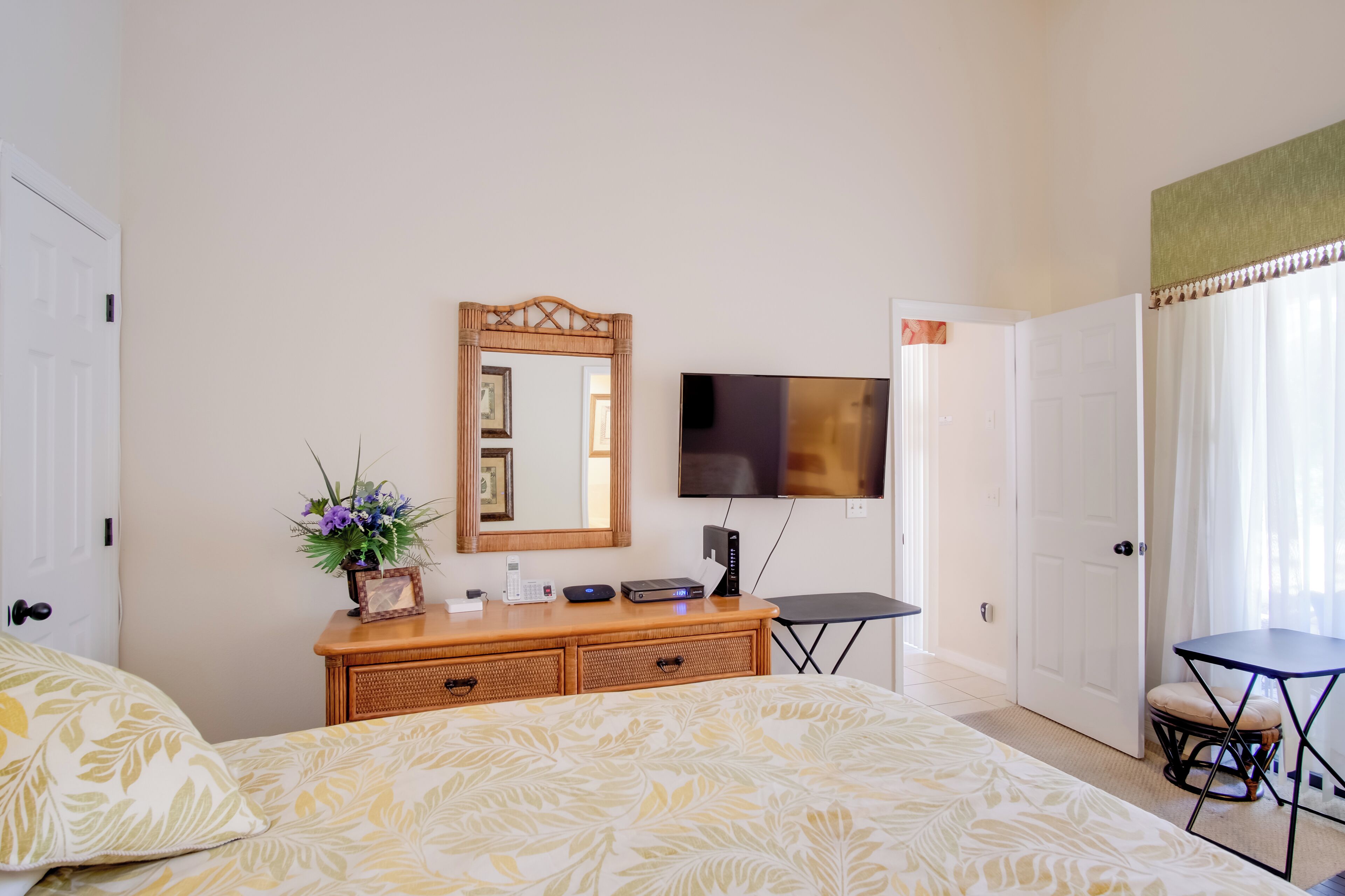 Un dormitorio con una cama, un aparador, un televisor, una mesita y una silla.