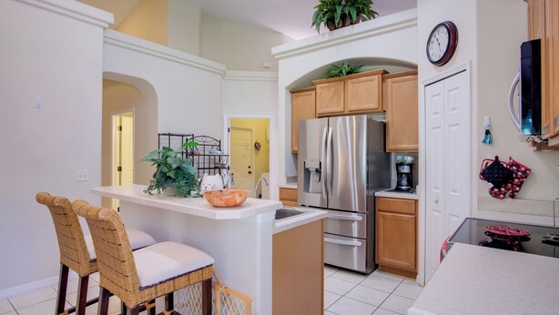 A modern kitchen with a central island, stainless steel appliances, and wooden cabinets. - Sunny Villa w/ Lanai: 17 Mi to Disney! (Davenport)