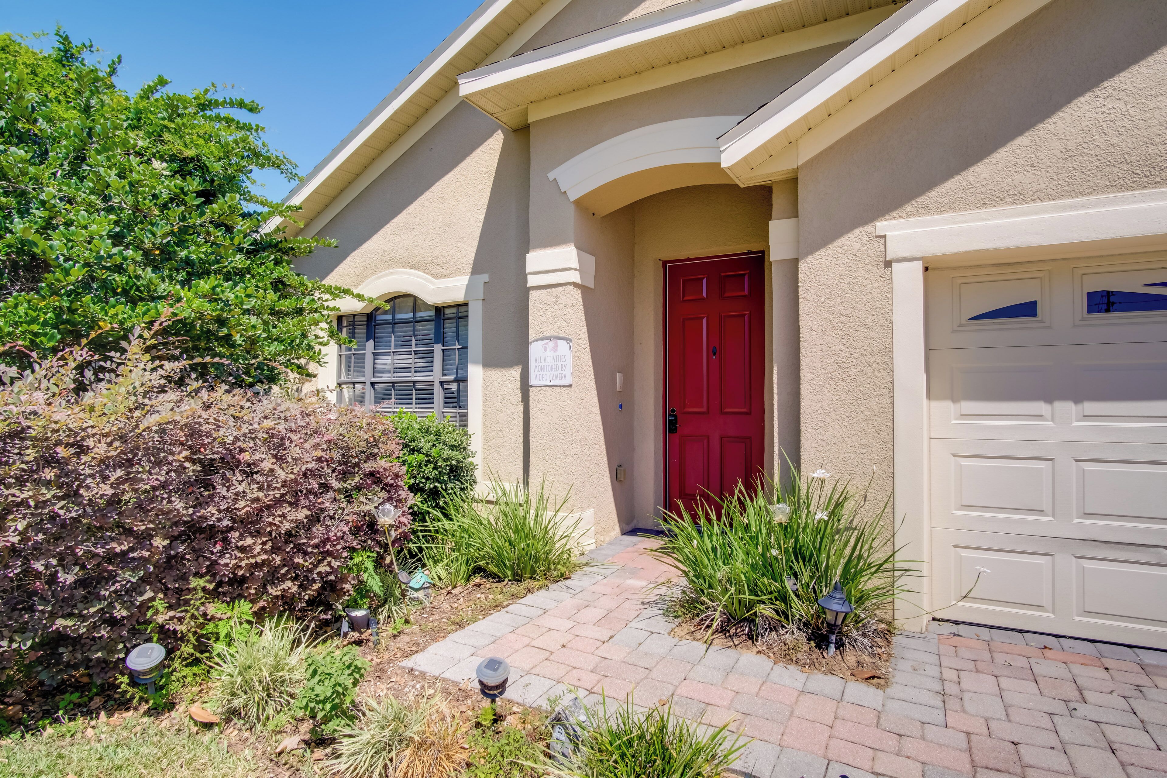 A residential house with a red door, a garage, and a paved driveway.