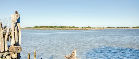 A calm body of water with wooden posts and a fence.