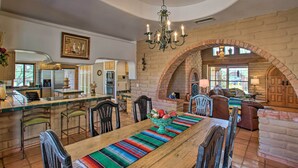 A spacious kitchen with a central island, a dining area with a long wooden table and chairs, and a cozy living area with a fireplace. - Pet-friendly Cave Creek Villa w/ Backyard Oasis! (Cave Creek)