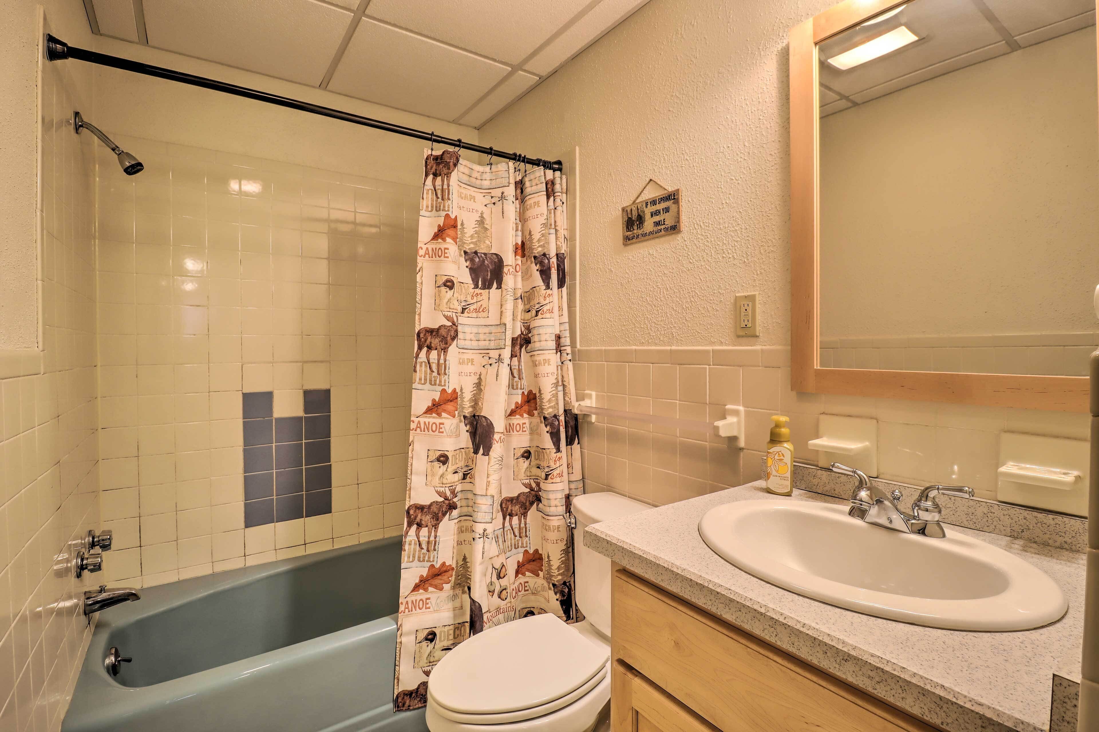 A bathroom with a bathtub, toilet, sink, and shower curtain with animal prints.