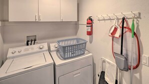 A laundry area with a washing machine, dryer, and a wall-mounted drying rack with cleaning supplies.
