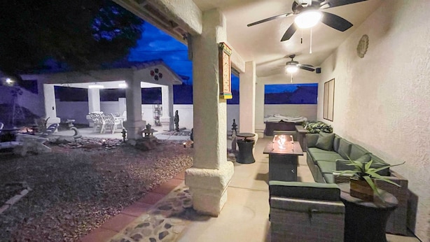 An outdoor patio area with a stone pathway, seating arrangements, and a ceiling fan.