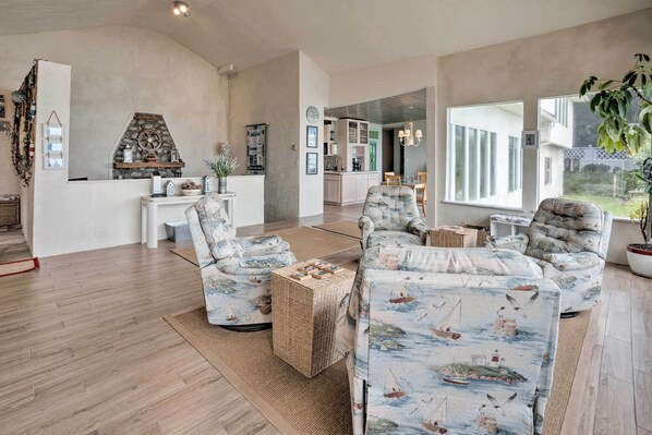 Un salón amplio con un ventanal grande, una chimenea y un rincón de comedor visible a través de una puerta abierta.