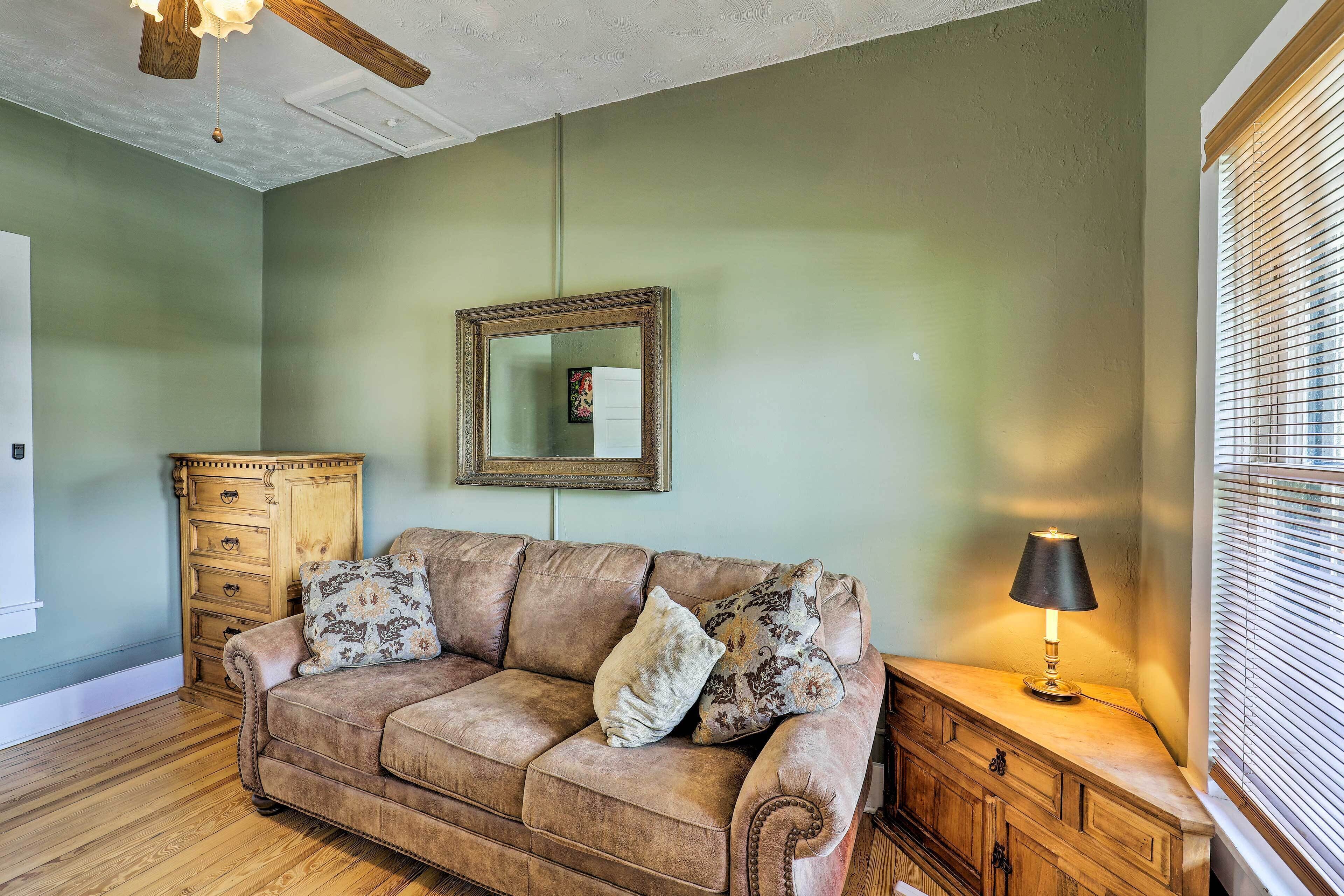 Una habitación con un sofá de cuero marrón, un armario de madera y una lámpara.
