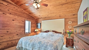 Une chambre aux murs lambrissés, avec un lit, une commode et un ventilateur de plafond.