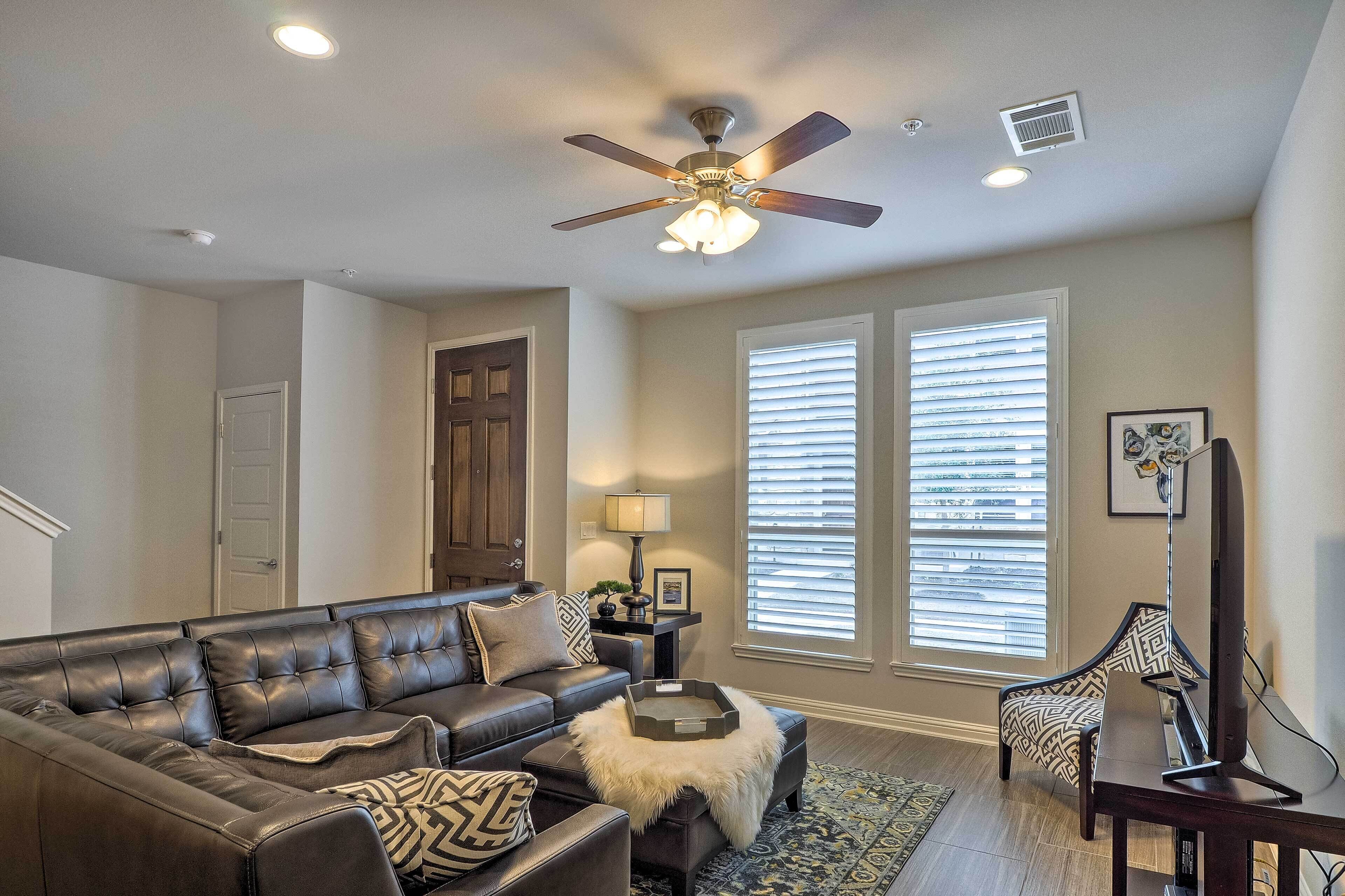 A living room with a sectional sofa, a coffee table, a floor lamp, and a ceiling fan.