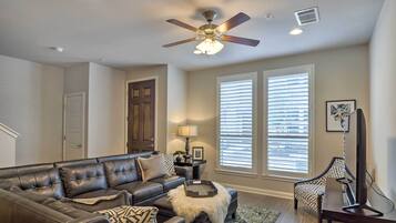 A living room with a sectional sofa, a coffee table, a floor lamp, and a ceiling fan.