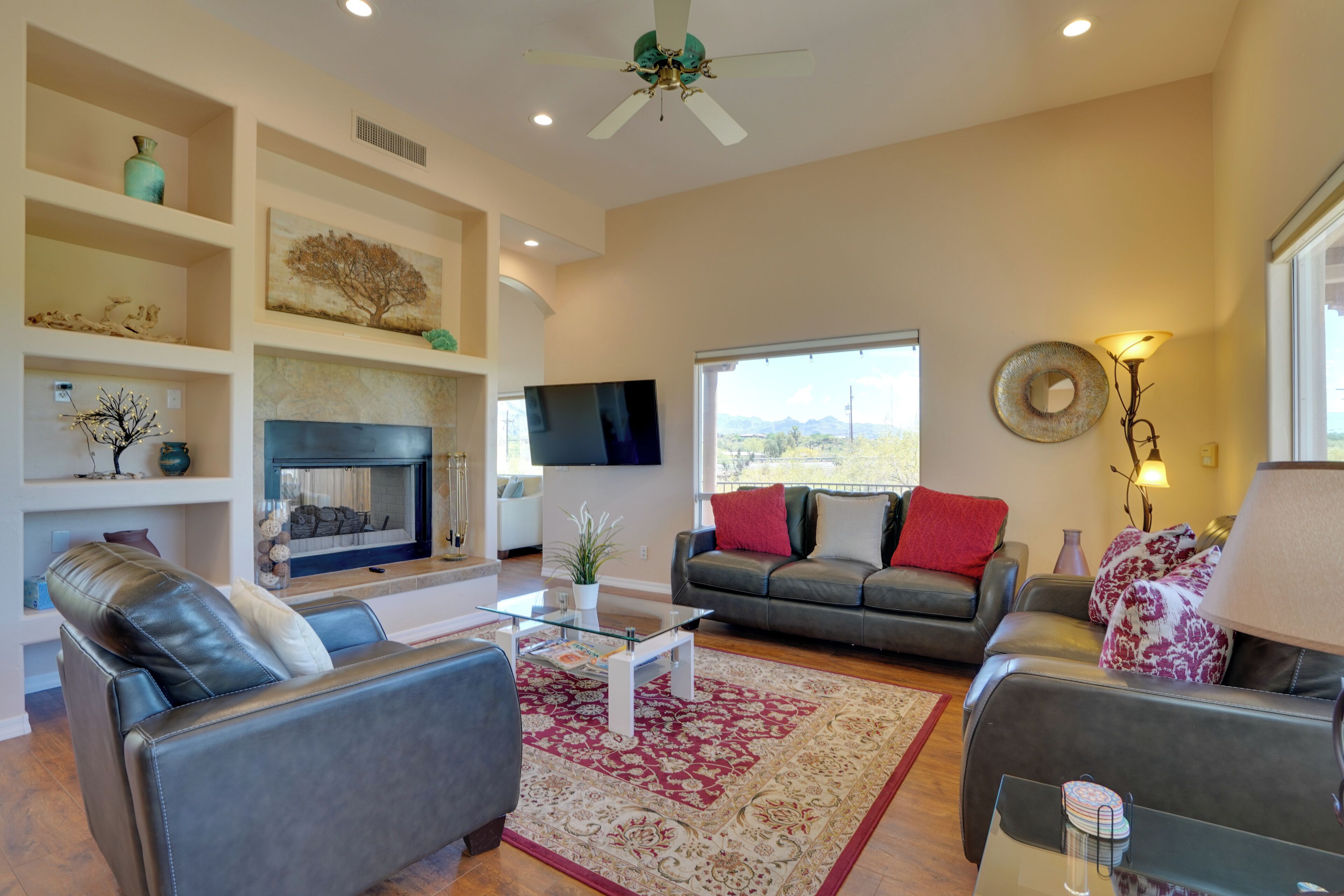 A modern living room with a fireplace, leather sofas, a glass coffee table, and a large window offering a view.