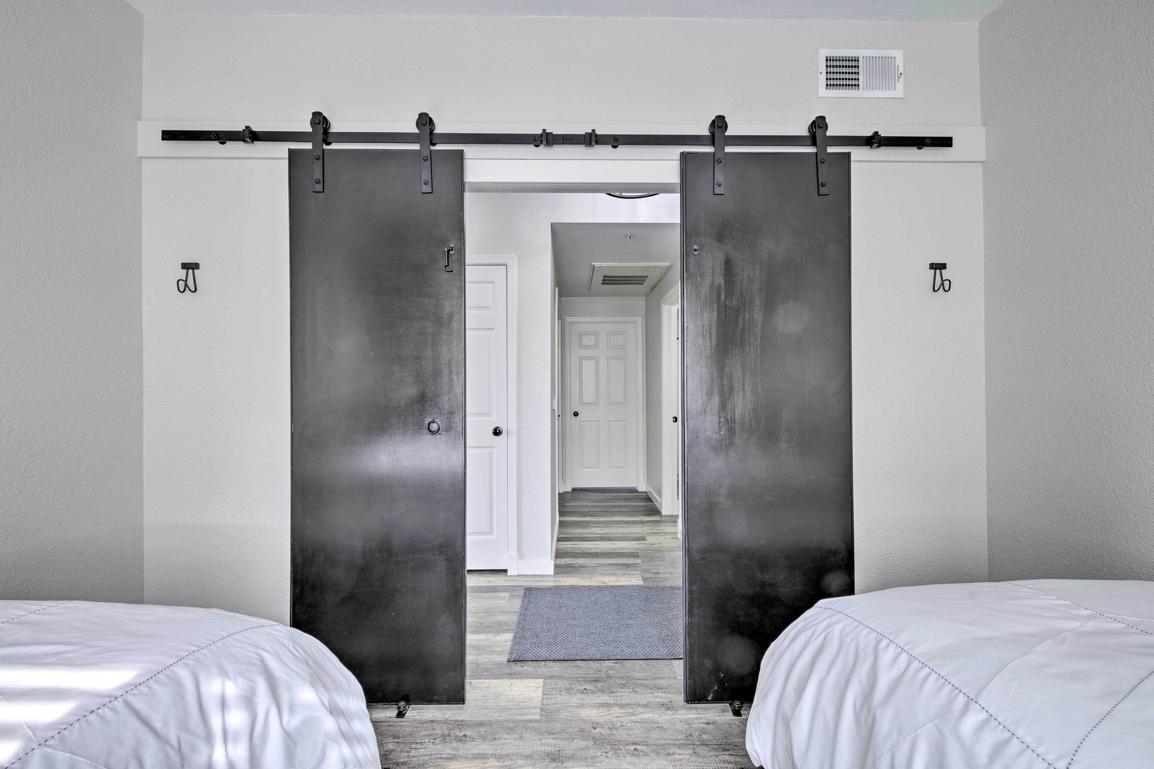 A bedroom with two beds, a sliding door, and a hallway leading to a door.
