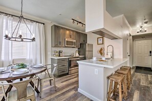 A modern kitchen with a central island, built-in appliances, and a dining area with a chandelier. - Modern Phoenix Condo w/ Resort Pool & Spa! (Phoenix)