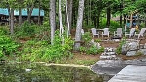 A cabin with a deck overlooking a pond, surrounded by trees. - Waterfront Denmark Complex w/ Dock on 12 Acres! (Denmark)
