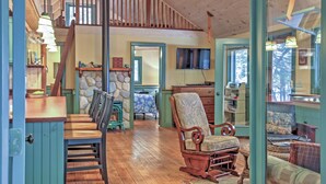 A cozy cabin interior with a dining area, a rocking chair, a television, and a stone wall. - Waterfront Denmark Complex w/ Dock on 12 Acres! (Denmark)