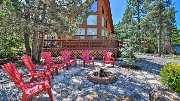 A cabin with a deck, red Adirondack chairs, and a fire pit surrounded by rocks. - Modern Mountain Chalet: Munds Park Retreat w/ Deck (Munds Park)