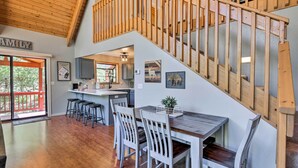 A spacious kitchen with a wooden staircase, white chairs, and a dining table. - Modern Mountain Chalet: Munds Park Retreat w/ Deck (Munds Park)