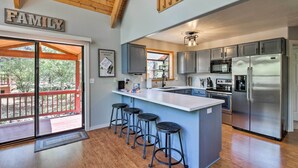 A modern kitchen with a large island, bar stools, stainless steel appliances, and a 'FAMILY' sign. - Modern Mountain Chalet: Munds Park Retreat w/ Deck (Munds Park)