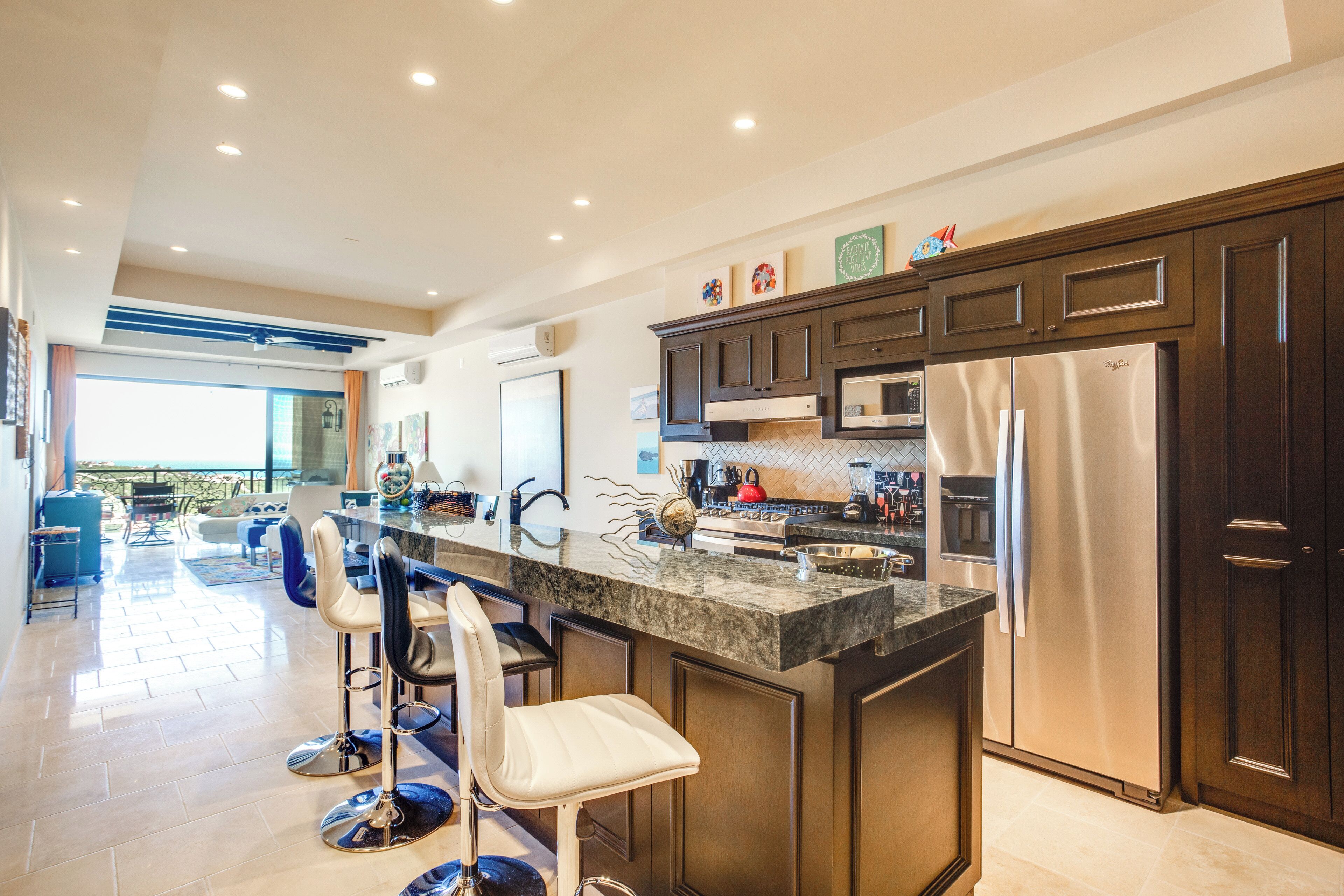 Una cocina moderna con armarios de madera oscura, electrodomésticos de acero inoxidable y una isla central con taburetes de bar.
